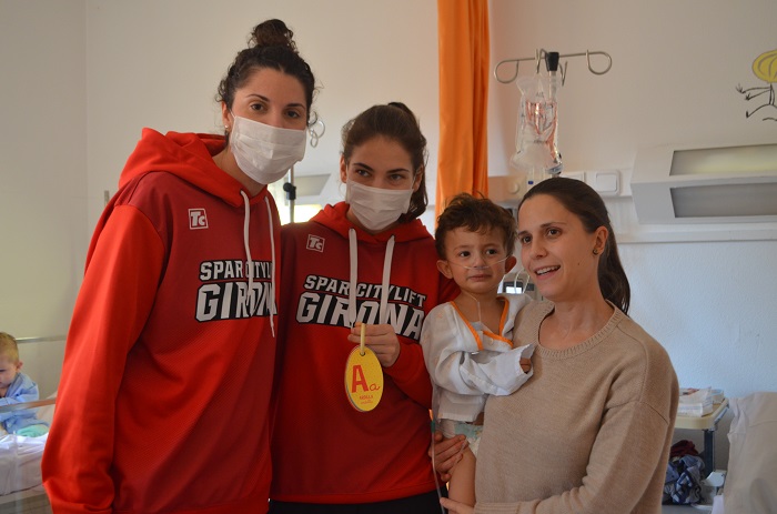 Jugadores de l'equip de bàsquet femení UNI Girona Spar Citylift visitant un nen ingressat a Pediatria