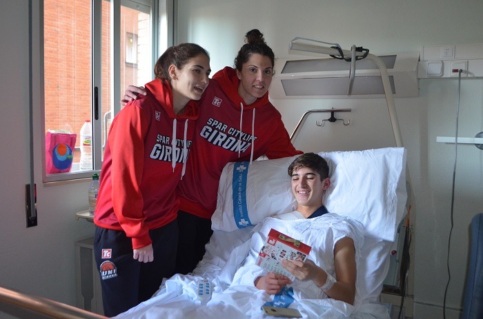 Jugadores de l'equip de bàsquet femení UNI Girona Spar Citylift visitant un nen ingressat a Pediatria